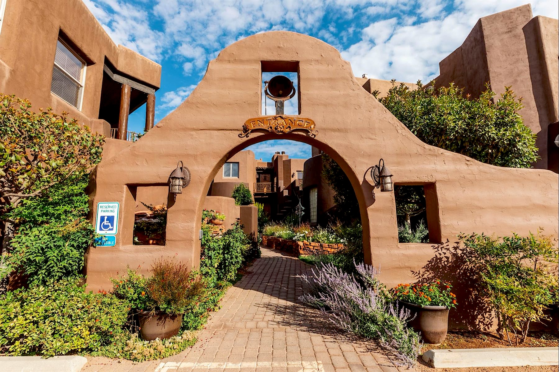 The adobe archway entrance to Adobe Grand Villas, with lavender and potted plants