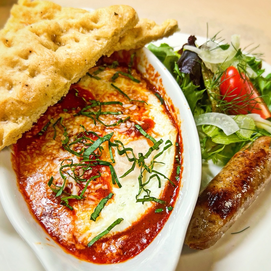 Eggs baked in tomato sauce with melted cheese and basil, focaccia, sausage and a fennel salad