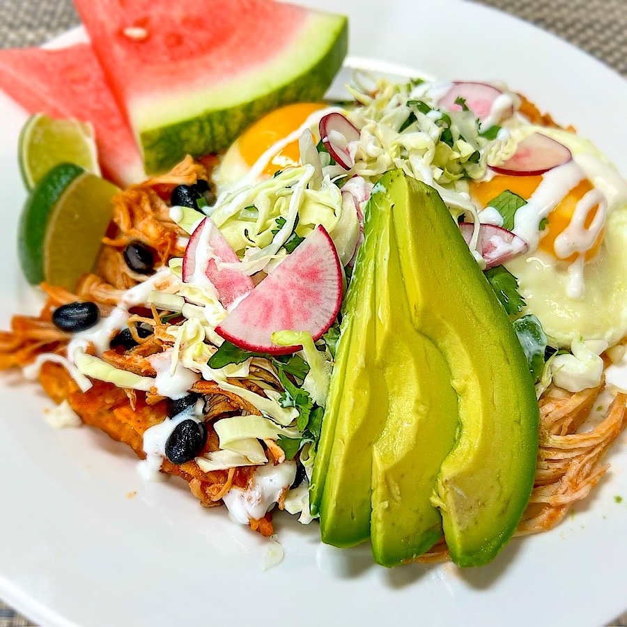 Chilaquiles with chicken tinga, over-easy eggs, avocado and lime crema