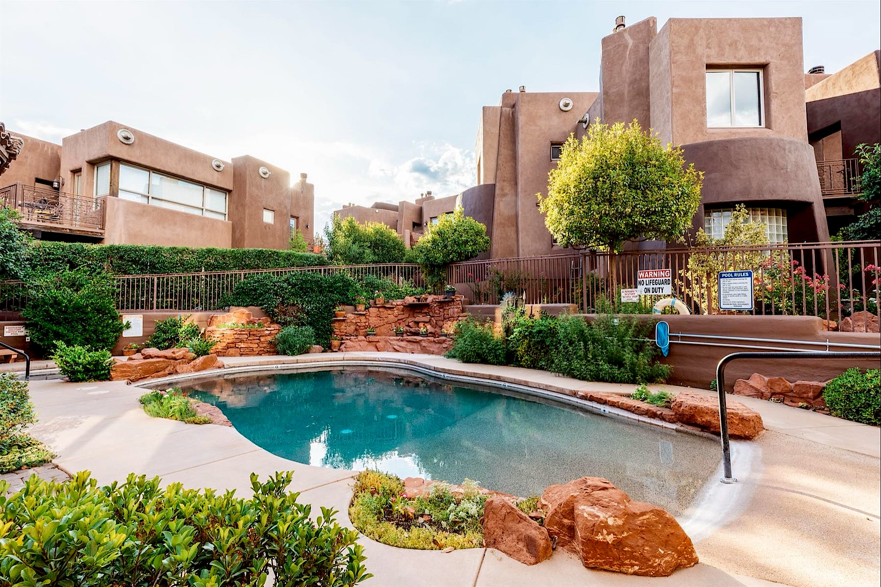 Heated outdoor pool edged with red rock beside the adobe villas