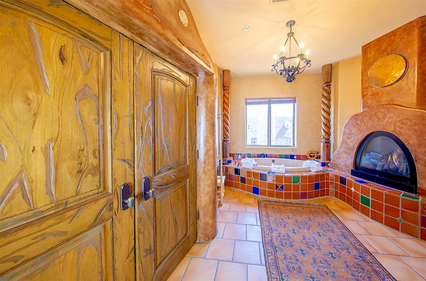 Cactus Flower villa jetted tub in colorful tile beside a kiva fireplace