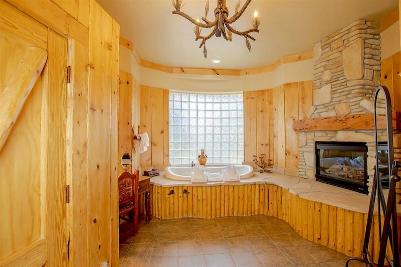 Whispering Pine villa jetted tub beside a stone fireplace